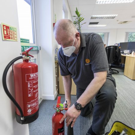 Team member at Scutum London fixing a fire extinguisher