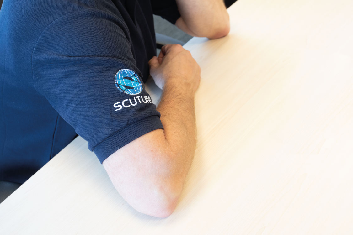 close up of a man's arm wearing a Scutum London tshirt 